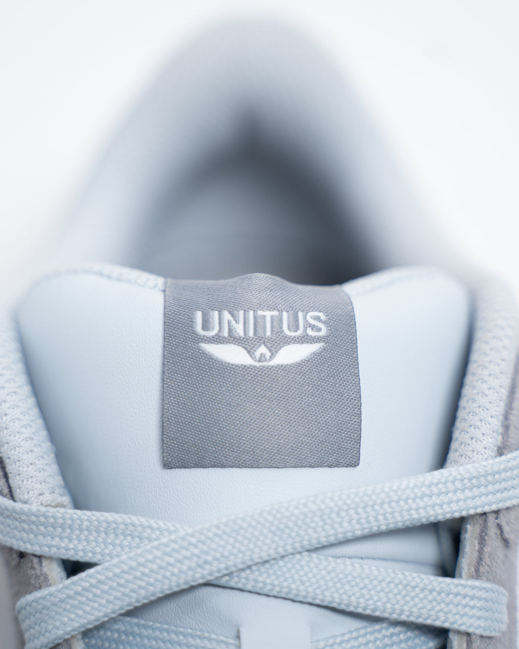Close-up of the Unitus tongue label and gray laces on the Immanuel 1 sneaker.